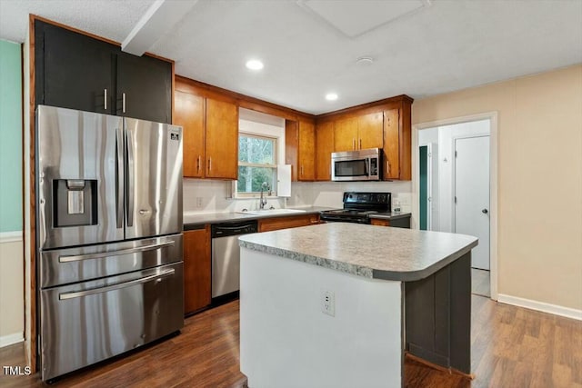 kitchen with dark wood-type flooring, stainless steel appliances, a center island, and sink