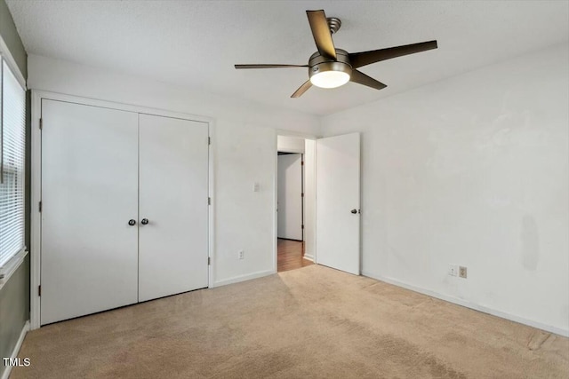 unfurnished bedroom featuring light colored carpet, ceiling fan, and a closet