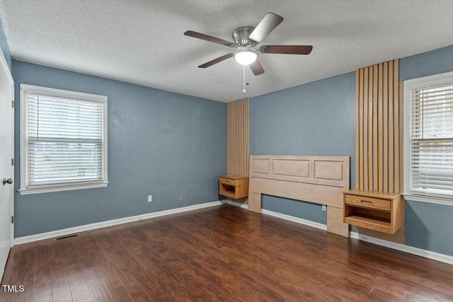 unfurnished living room featuring dark hardwood / wood-style flooring, a textured ceiling, and ceiling fan