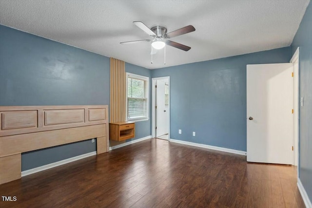 empty room with ceiling fan, dark wood-type flooring, and a textured ceiling