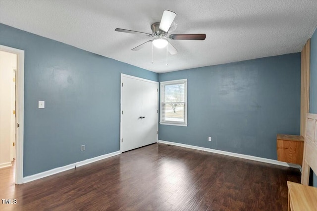 unfurnished bedroom featuring ceiling fan, dark hardwood / wood-style floors, and a textured ceiling