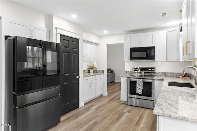 6309 Cape Charles Dr, Raleigh, NC 27617 - kitchen with light stone counters, white cabinets, sink, and black appliances
