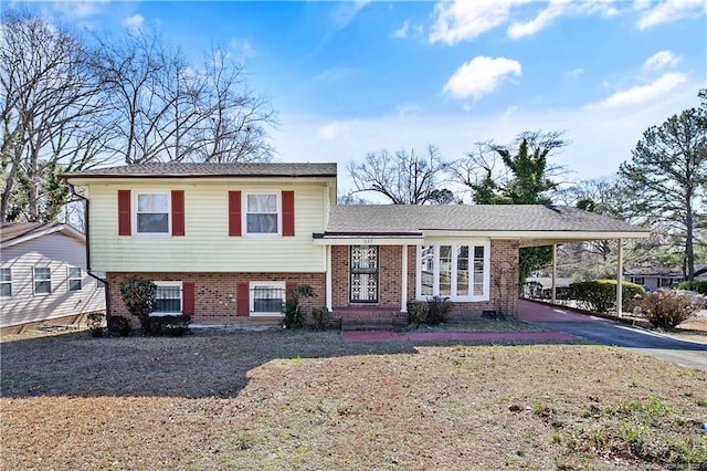 tri-level home featuring driveway, brick siding, and an attached carport