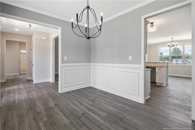 unfurnished dining area featuring baseboards, ornamental molding, dark wood-style flooring, and a notable chandelier