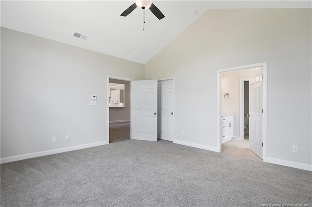 unfurnished bedroom featuring high vaulted ceiling, baseboards, light colored carpet, and visible vents