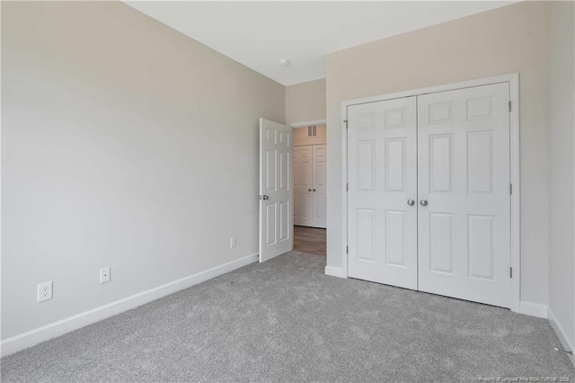 unfurnished bedroom with baseboards, carpet flooring, visible vents, and a closet