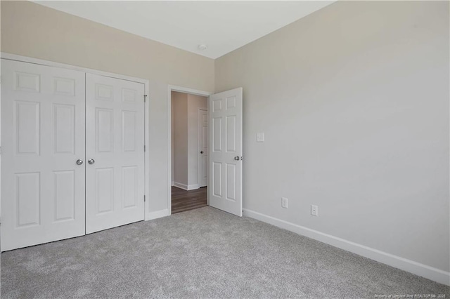 unfurnished bedroom featuring carpet floors, baseboards, and a closet
