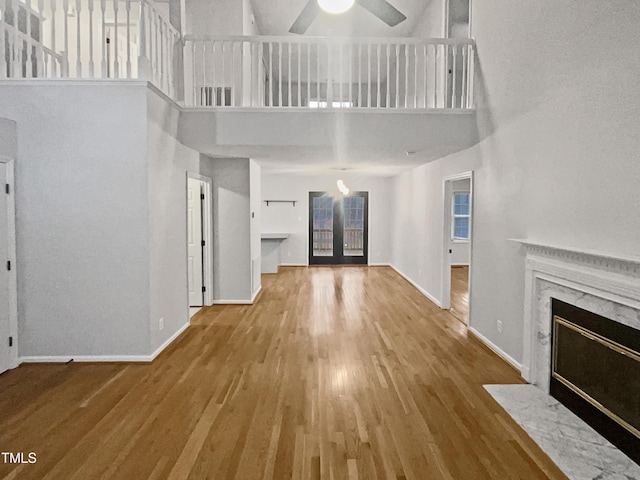 unfurnished living room with a high ceiling, hardwood / wood-style floors, ceiling fan, and a premium fireplace