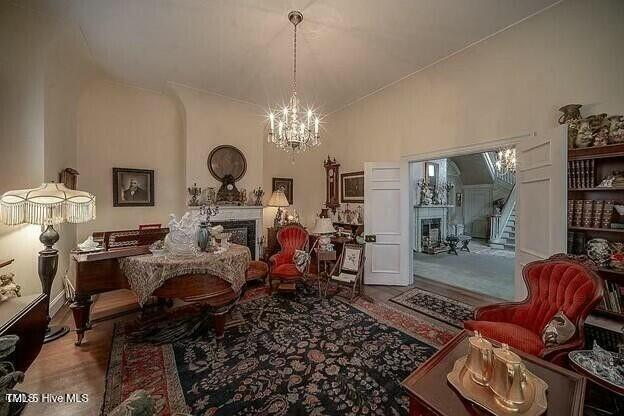 living area featuring an inviting chandelier, high vaulted ceiling, and hardwood / wood-style floors