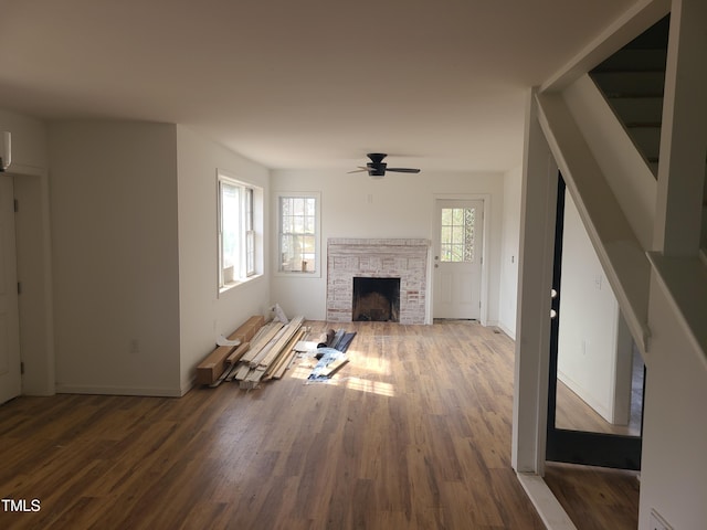 unfurnished living room featuring ceiling fan, hardwood / wood-style flooring, a fireplace, and a healthy amount of sunlight