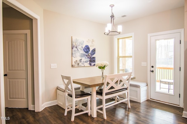 dining space with dark wood-type flooring, visible vents, a notable chandelier, and baseboards