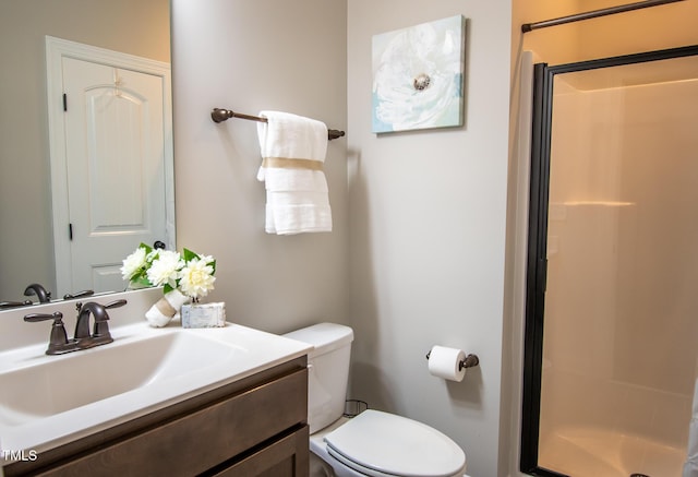 bathroom with toilet, a shower stall, and vanity