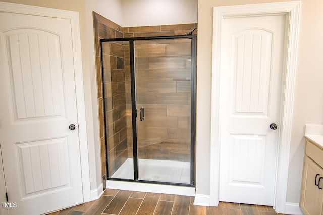 bathroom featuring a stall shower, wood finished floors, vanity, and baseboards