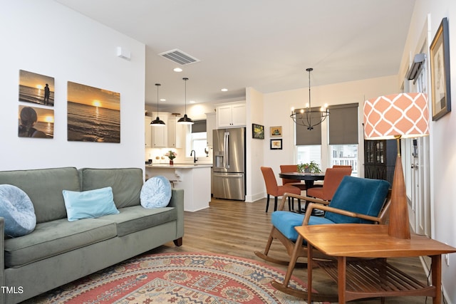 living room with hardwood / wood-style flooring, sink, and a notable chandelier