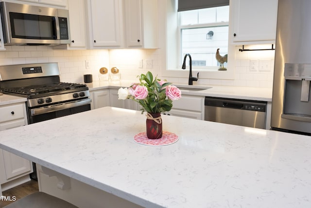 kitchen with white cabinetry, sink, light stone countertops, and appliances with stainless steel finishes