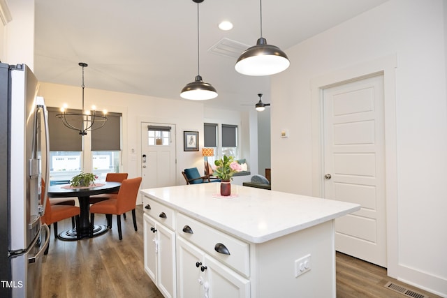 kitchen featuring a kitchen island, pendant lighting, white cabinetry, stainless steel fridge, and dark wood-type flooring