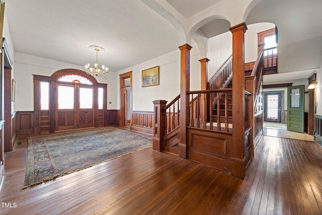 entrance foyer with ornate columns, wood-type flooring, and a chandelier