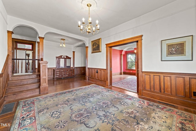 spare room with decorative columns, dark hardwood / wood-style floors, and a chandelier