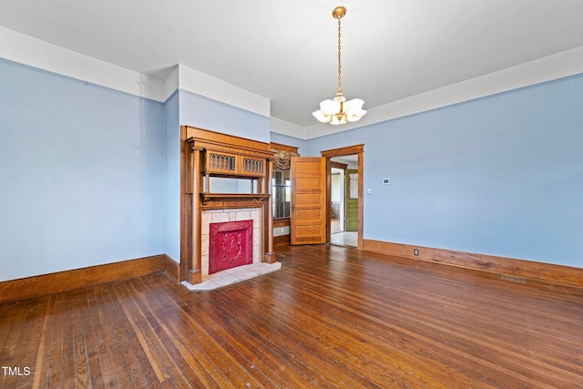unfurnished living room with a tile fireplace, dark wood-type flooring, and a chandelier