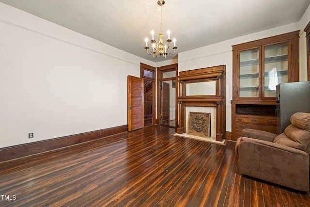 unfurnished living room featuring a tiled fireplace, dark hardwood / wood-style floors, and a chandelier