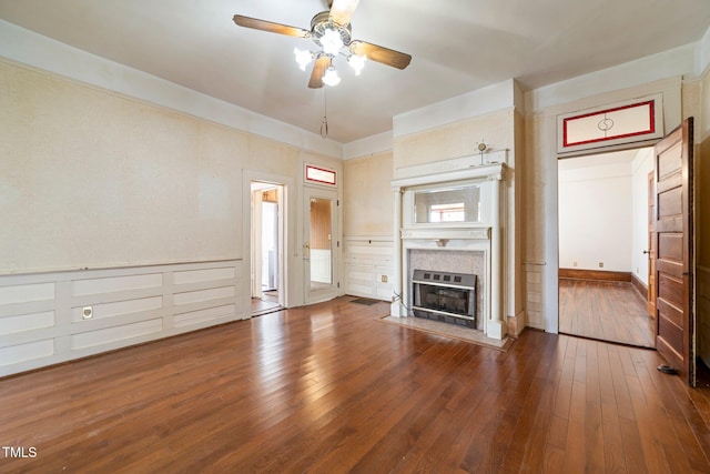 unfurnished living room featuring a tiled fireplace, dark hardwood / wood-style floors, and ceiling fan