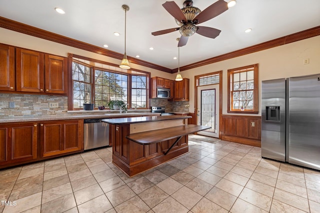 kitchen with sink, stainless steel appliances, decorative backsplash, a kitchen island, and decorative light fixtures