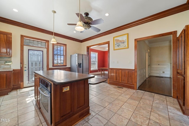 kitchen featuring a center island, hanging light fixtures, light tile patterned floors, ornamental molding, and stainless steel appliances