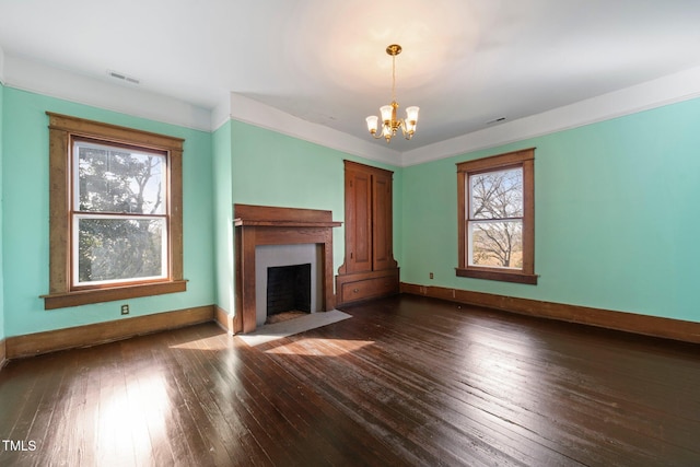 unfurnished living room featuring an inviting chandelier and dark hardwood / wood-style floors