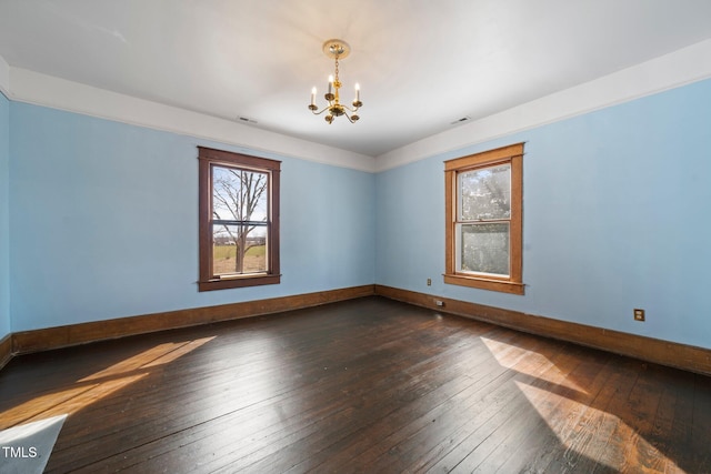 unfurnished room with a notable chandelier and dark hardwood / wood-style floors