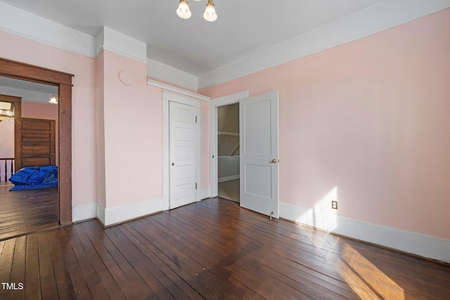 spare room featuring an inviting chandelier and dark hardwood / wood-style floors