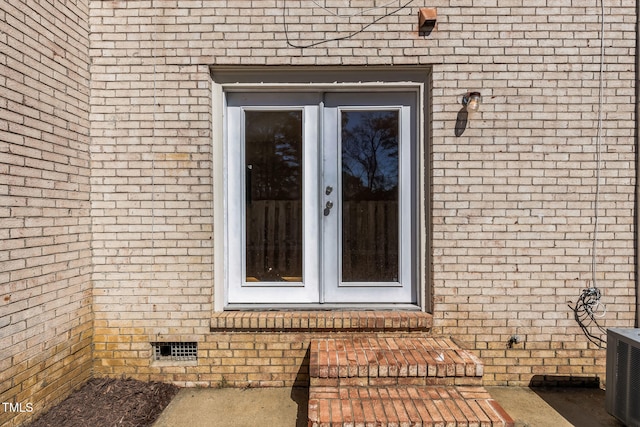 doorway to property with crawl space, brick siding, and central AC