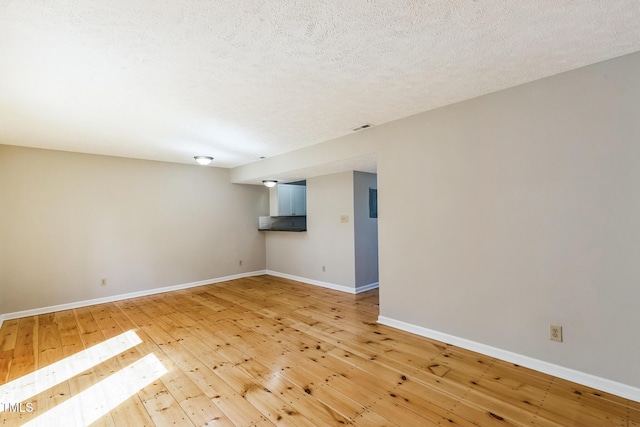 unfurnished room with light wood-style flooring, visible vents, baseboards, and a textured ceiling