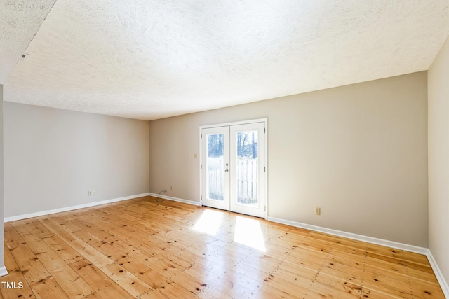 spare room featuring french doors, a textured ceiling, baseboards, and wood-type flooring