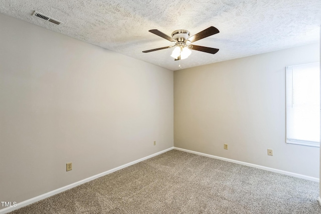 spare room featuring visible vents, a textured ceiling, carpet, baseboards, and ceiling fan