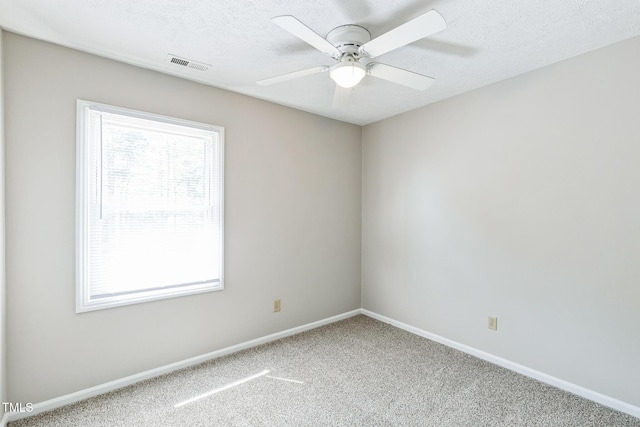 carpeted spare room featuring visible vents, a textured ceiling, baseboards, and ceiling fan