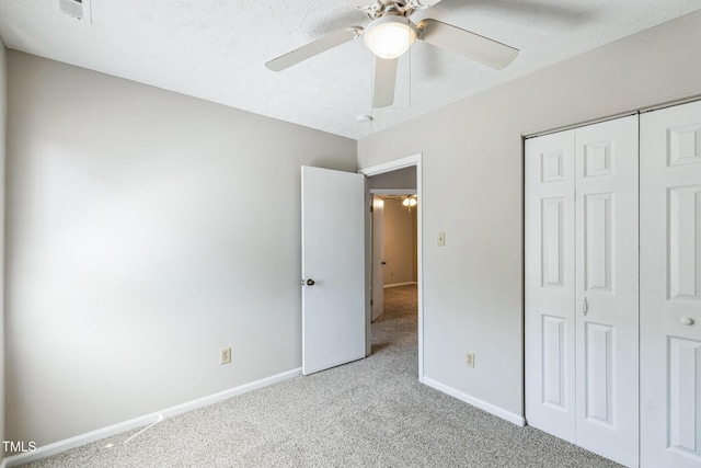 unfurnished bedroom with baseboards, carpet, a closet, a textured ceiling, and a ceiling fan