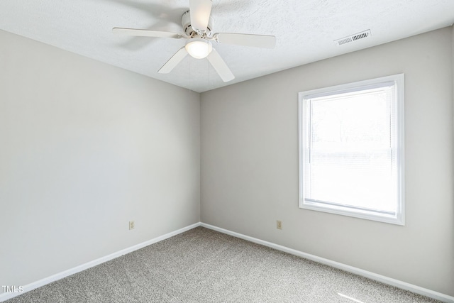 empty room with a ceiling fan, visible vents, baseboards, a textured ceiling, and carpet flooring