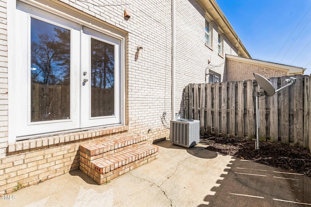 view of patio with cooling unit, french doors, and fence