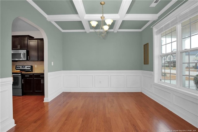 unfurnished dining area featuring an inviting chandelier, coffered ceiling, light hardwood / wood-style floors, and beamed ceiling