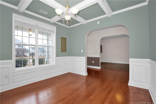 empty room featuring beam ceiling, coffered ceiling, dark wood-type flooring, and a chandelier