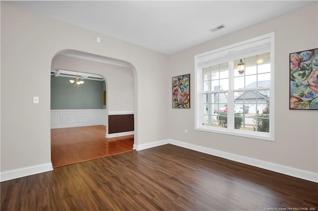 spare room featuring dark wood-type flooring and a notable chandelier