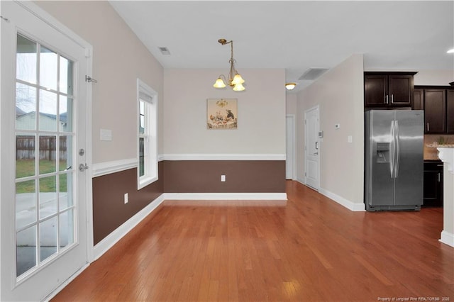 unfurnished dining area with hardwood / wood-style floors and a notable chandelier