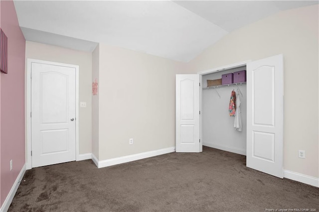 unfurnished bedroom featuring lofted ceiling, a closet, and dark colored carpet