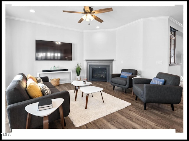 living room featuring a glass covered fireplace, ornamental molding, a ceiling fan, and wood finished floors