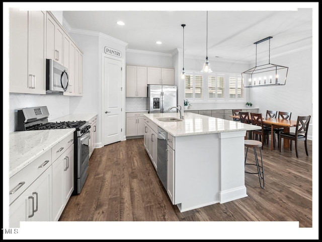 kitchen featuring a sink, a center island with sink, ornamental molding, appliances with stainless steel finishes, and dark wood-style flooring