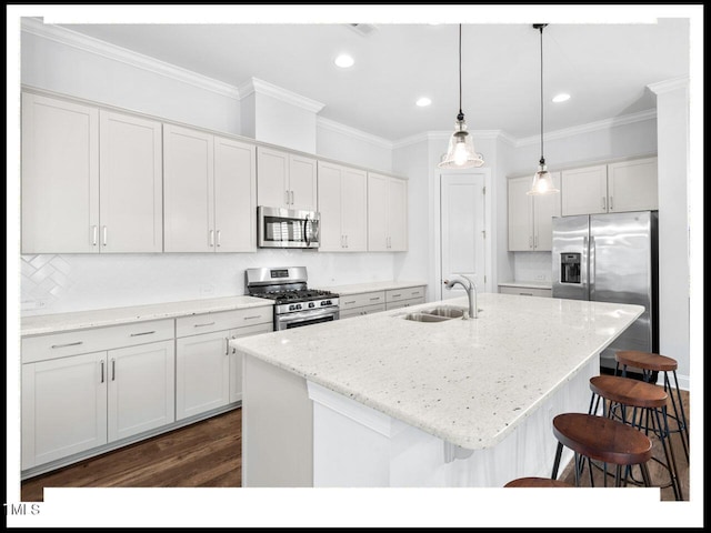 kitchen with a center island with sink, a sink, stainless steel appliances, a breakfast bar area, and hanging light fixtures