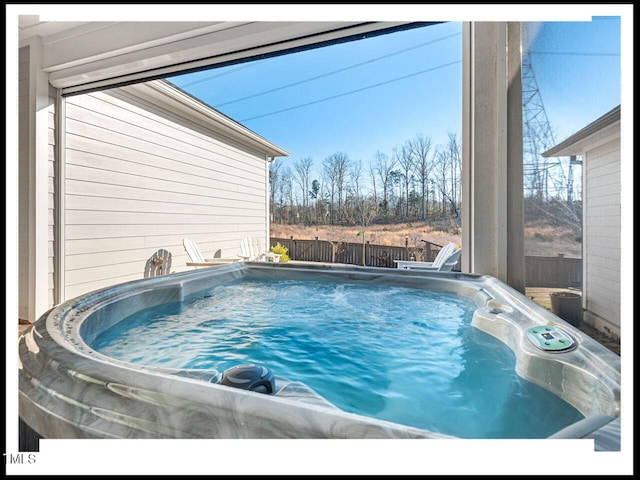 view of pool with fence and a hot tub