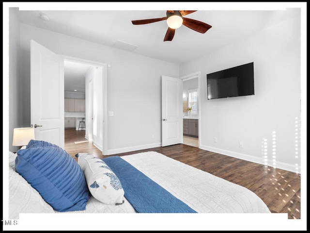 bedroom with ceiling fan, ensuite bathroom, baseboards, and wood finished floors