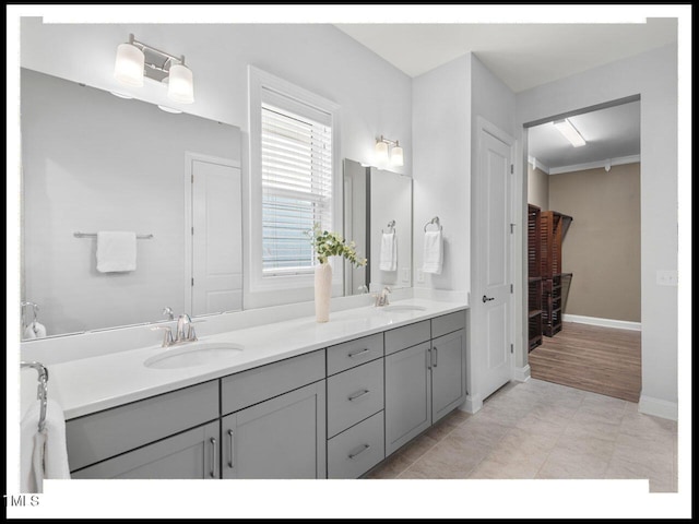 bathroom featuring double vanity, baseboards, and a sink