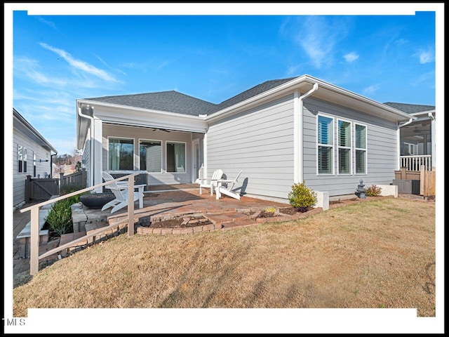 rear view of house featuring fence, a shingled roof, a lawn, and a patio area